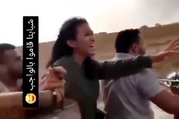 In this image from video obtained by the Associated Press, Noa Argamani is seized by members of the Hamas militant group on Oct. 7. The writing in Arabic at left in the video posted on social media features a laughing emoji and reads, “Our guys have done their duty.”