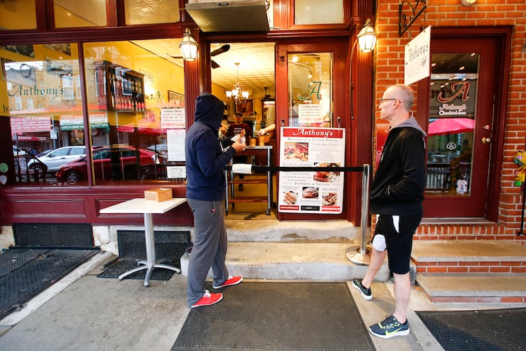 Customers waiting for their coffee and food outside Anthony's Italian Coffee House, which is among the Italian Market merchants offering free delivery.