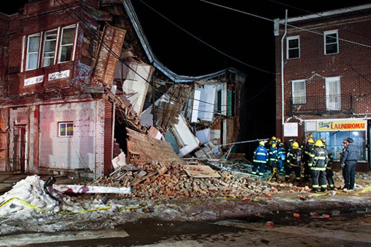 Firefighters use a pole to insert a listening device as they make sure no one is trapped in the debris after row house collapsed on Ogontz Avenue near Limekiln Pike in the East Germantown section of Philadelphia on Sunday, Feb. 23, 2014. (For the Daily News/ Joseph Kaczmarek)