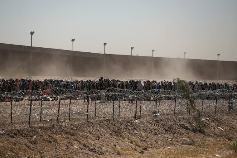 Migrants line-up between a barbed-wire barrier and the border fence at the US-Mexico border, as seen from Ciudad Juarez, Mexico, on Tuesday. The U.S. is preparing for the Thursday end of the Title 42 policy.