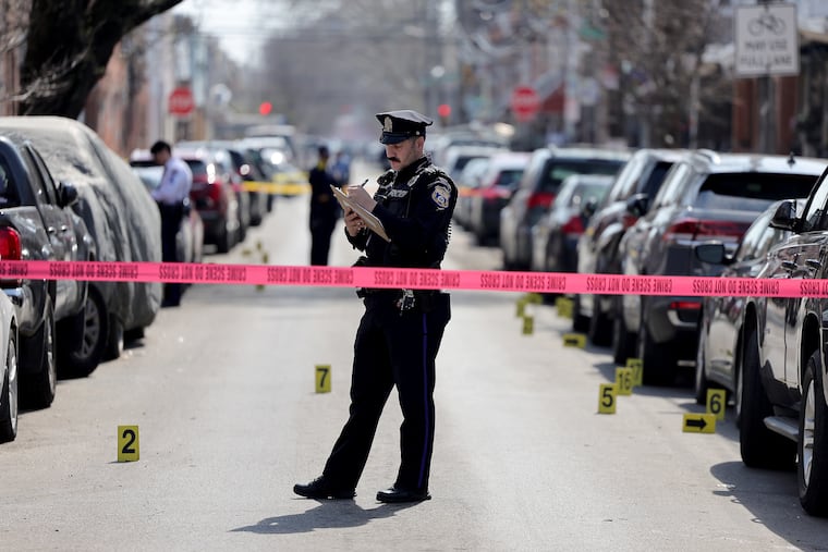 A police officer takes notes at the scene of a fatal shooting in South Philadelphia Sunday.
