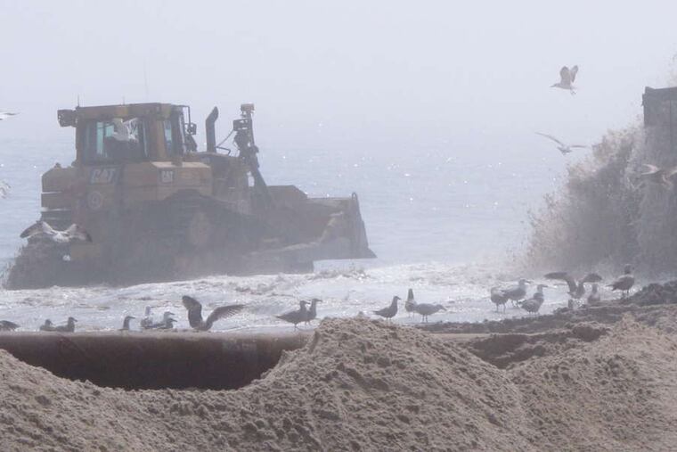 A bulldozer pushes newly pumped sand on a fog-shrouded beach in Ship Bottom, N.J. The Army Corps of Engineers started work this week on the $128 million project.