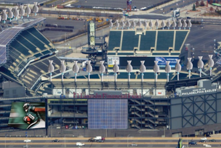An artist’s rending of Lincoln Financial Field with the addition of wind turbines around the upper edge and solar panels covering portions of the stadium roof and facade, expected to be installed by September.