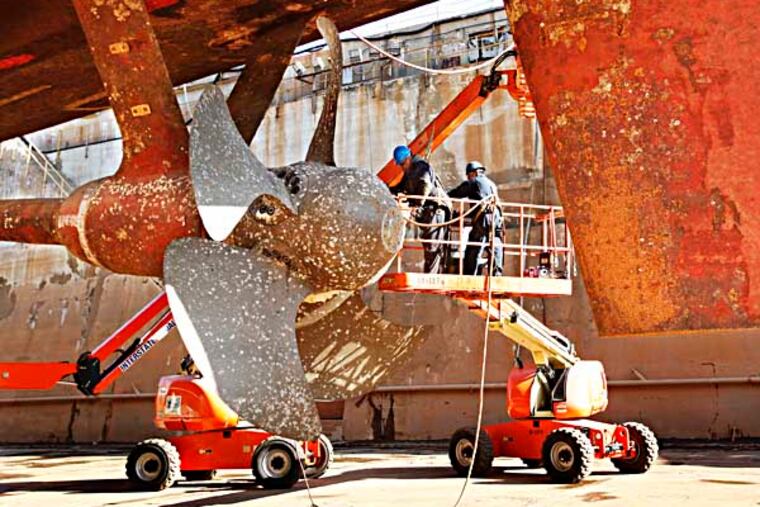 Workers begin to remove the propeller. The Navy is paying Philadelphia Ship Repair to salvage parts from decomissioned frigates. They begin with parts from the decomissioned USS Hawes FFG53 in dry dock at the Philadelphia Navy Yard. November 26, 2013.( MICHAEL S. WIRTZ / Staff Photographer)
