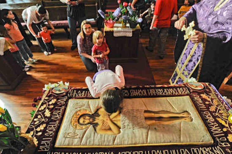 In an Orthodox tradition for what is called Great and Holy Friday, children kiss a representation of Jesus' shroud and then a cross held by the Rev. Milorad Orlic, pastor of the Serbian Orthodox Church of St. Nicholas, which recently moved to Elkins Park. More photographs, B11.