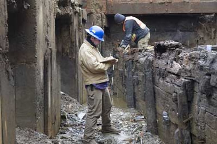 Archaeologists Jeff Harbison, front, and Alex Devries, back, record details on the dig site of the old wood-sided Aramingo Canal, built in the 1840's, which has been discovered behind the Port Richmond Village shopping center. (Ed Hille / Staff Photographer)