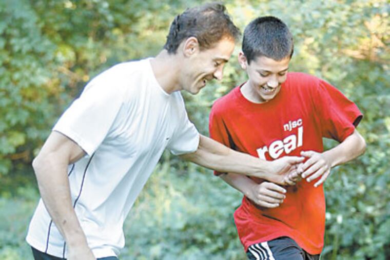 Jarrod Skole, a high school freshman, and his father, Gary, play soccer in their backyard. The two wrote “Imagine What’s Possible,” a child’s-eye view of visualization - the technique of using imagery to lessen anxiety and even pain. (AKIRA SUWA / Staff Photographer)