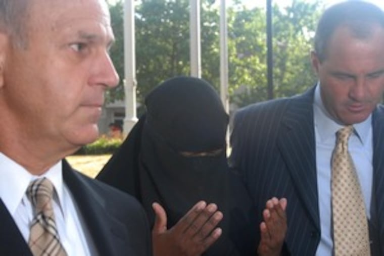 Flanked by her lawyers, a veiled Myra Morton arrived yesterday at Montgomery County Courthouse to surrender on charges of murdering her husband on Sunday.