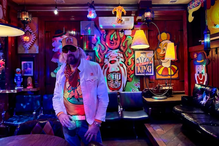 The owner of Neon Clown Dream Lounge, who goes by Chicken, poses in front of a clown painting he did for the bar, located above Kung Fu Necktie at 1248 N. Front Street.