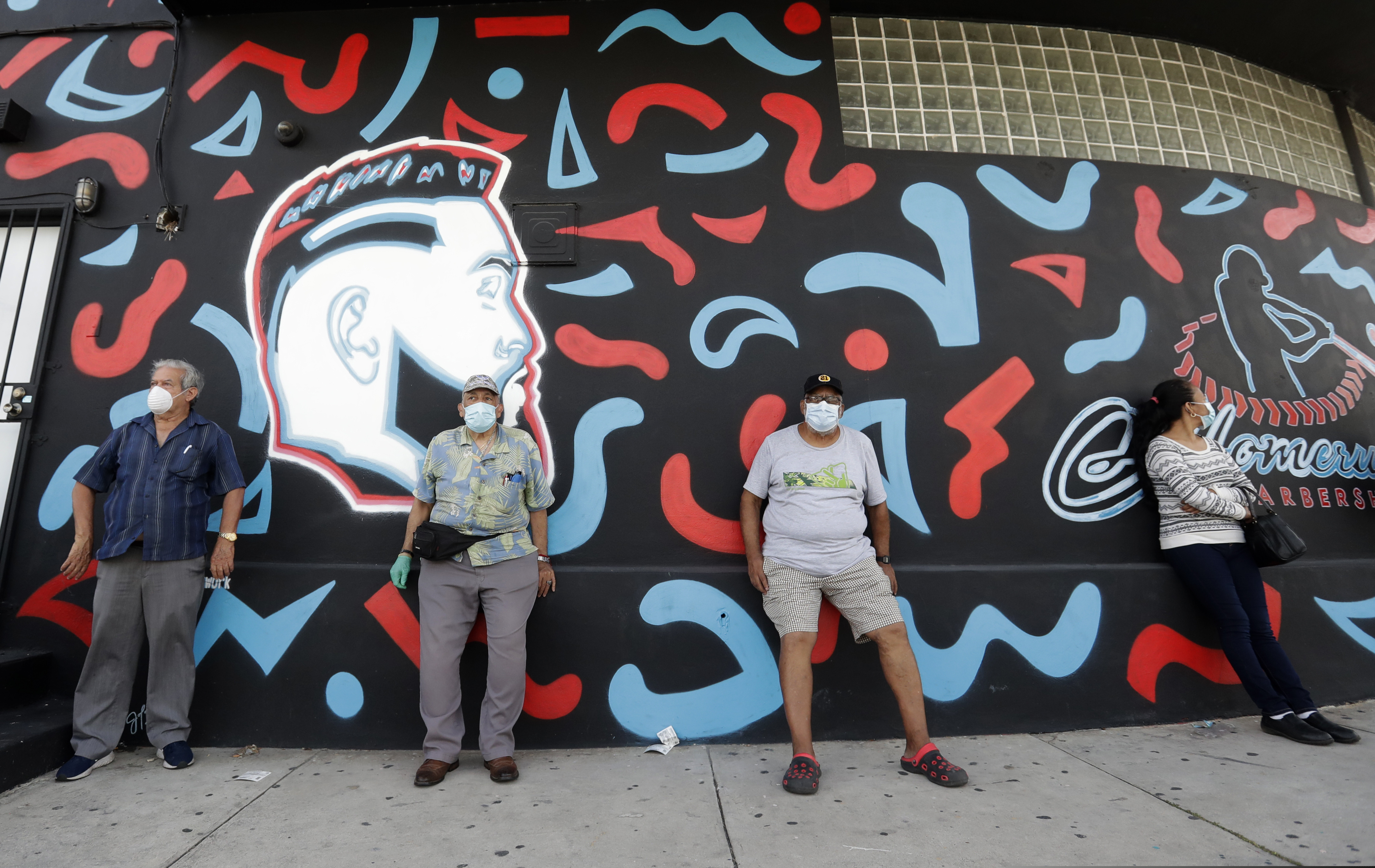 People, social distancing and wearing masks to prevent the spread of the new coronavirus, wait in line at a mask distribution event.