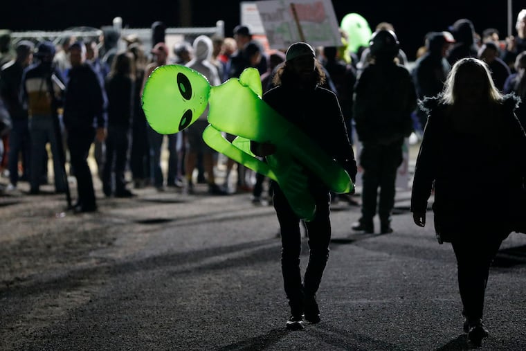 A mans holds an inflatable alien at an entrance to the Nevada Test and Training Range near Area 51 Friday, Sept. 20, 2019, near Rachel, Nev. People gathered at the gate inspired by the "Storm Area 51" internet hoax. (AP Photo/John Locher)