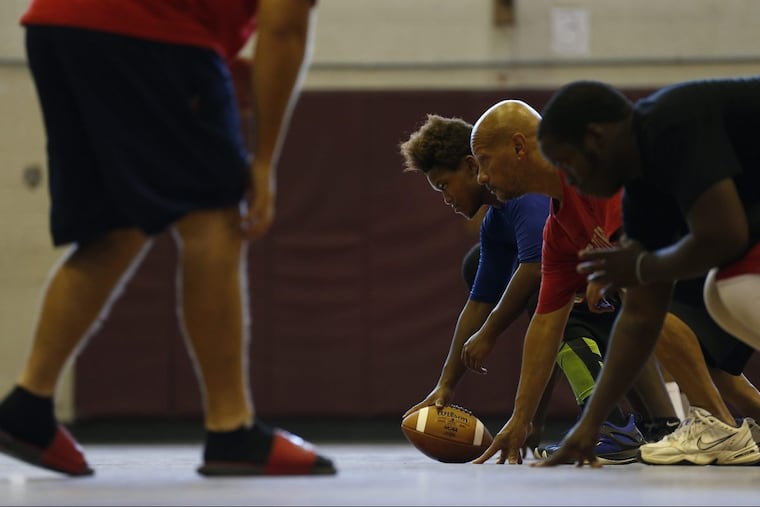 Darell Young, center, prepares to snap the ball during Strawberry Mansion High School football practice in Philadelphia, PA.