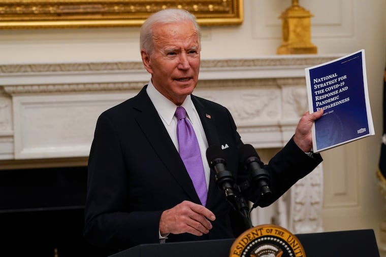 President Joe Biden holds up a copy of his coronavirus pandemic response plan at a news conference in the White House.