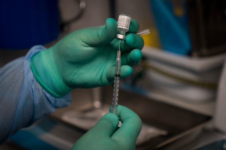 In this Aug. 26 photo, Parsia Jahanbani prepares a syringe with the Pfizer COVID-19 vaccine in a mobile vaccine clinic operated by Families Together of Orange County in Santa Ana, Calif.