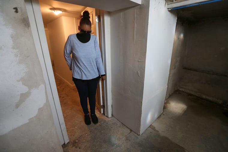 Linda Watson covers her nose because she can’t stand the smell after sewage backed up into the basement of the house she is renting in the Port Richmond section of Philadelphia. Watson’s landlord sent her an eviction notice after she withheld rent due to the conditions.