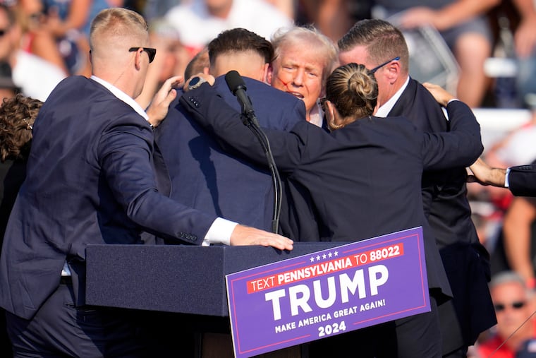 Republican presidential candidate former President Donald Trump is surrounded by Secret Service after an assassination attempt at a campaign event in Butler, Pa., on July 13, 2024.