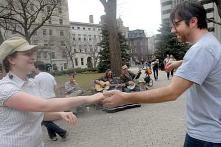 Erin Kroll and Dan Short dance in Rittenhouse Square while Jay Berkow
plays guitar and Sam Adams plays banjo on a nearby bench. (April Saul / Staff Photographer)
