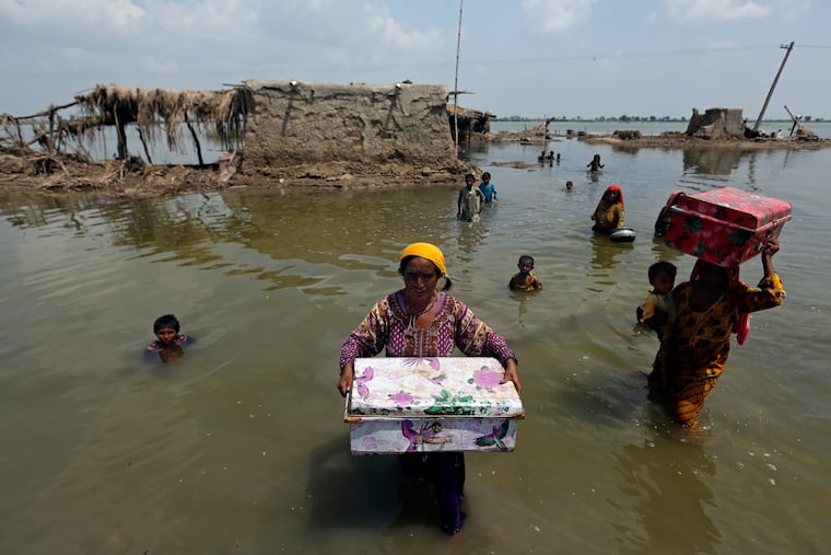 Women carry belongings salvaged from their flooded home after monsoon rains, in the Qambar Shahdadkot district of Sindh Province, of Pakistan, Sept. 6, 2022. From drought to floods and sea level rise, the cost of damage caused by climate change will only get higher as the world warms, sparking concerns from both top officials and activists about how to pay for it.