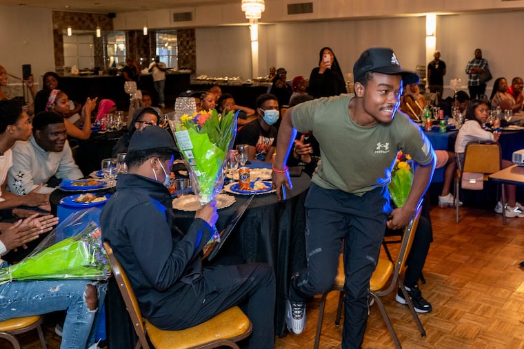 Lateef Haddad (right) gets up to accept his flowers, plaque, and City Council citation at the Aug. 22, 2022, graduation of students who completed Unity in the Community's Carpentry Academy.