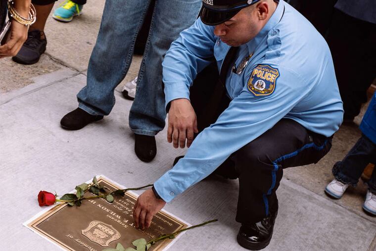 Officer Mike Rivera kneels at a plaque honoring slain Officer Robert Wilson III.