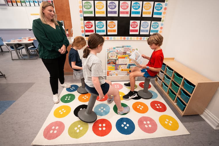 First-grade teacher Kelly Carroll, Thea Wroblewski, Emilia Stack, and Joseph Sprandio in a classroom at Our Mother of Consolation school in Chestnut Hill. The building's interior was destroyed by fire in 2023. The school raised millions and is about to open a new year in a dramatically improved space.