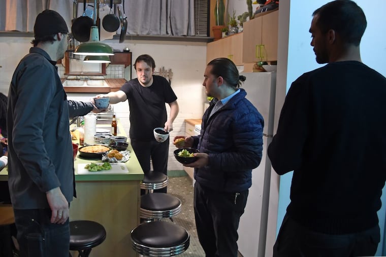Tenant Joe Leroux (center) hands out bowls in the kitchen of apartment he shares with Stacey Lee Webber (not shown).