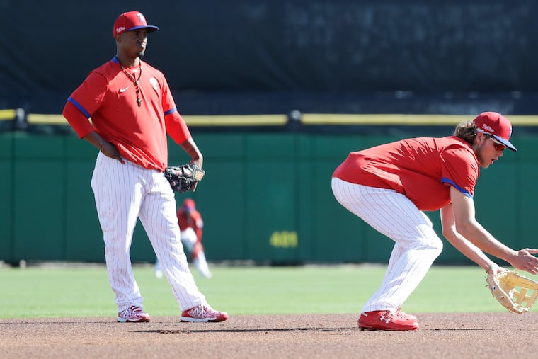 Jean Segura, left, watches as Phillies top prospect Alec Bohm takes a grounder at third base before Sunday's spring-training game against the Pittsburgh Pirates in Clearwater, Fla.