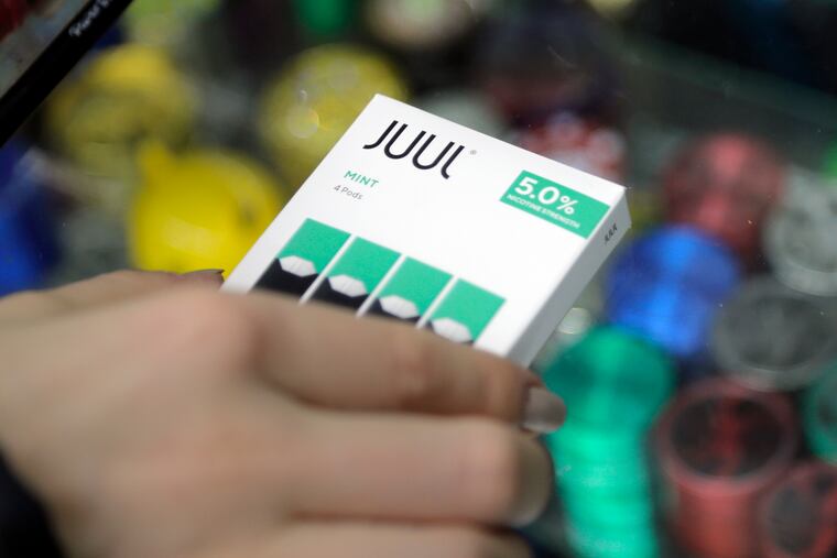 A woman buys refills for her Juul at a smoke shop in New York. The e-cigarette maker Juul Labs said Thursday that it will halt sales of its best-selling mint-flavored vaping pods.