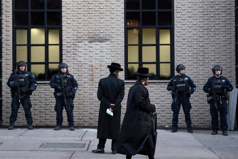 Orthodox Jewish men pass New York City police guarding a Brooklyn synagogue in 2019 prior to a funeral for Mosche Deutsch, a rabbinical student from Brooklyn who was killed in a shooting at a Jersey City, N.J., market.
