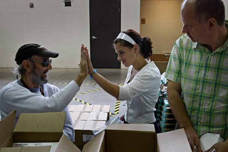 Sarah Beck (center), 16, from the Coatesville Youth Initiative Service Corps, high-fives worker Mike Tratzer (left) while Steve Whitehead (right) watches. (Michael S. Wirtz / Staff Photographer)