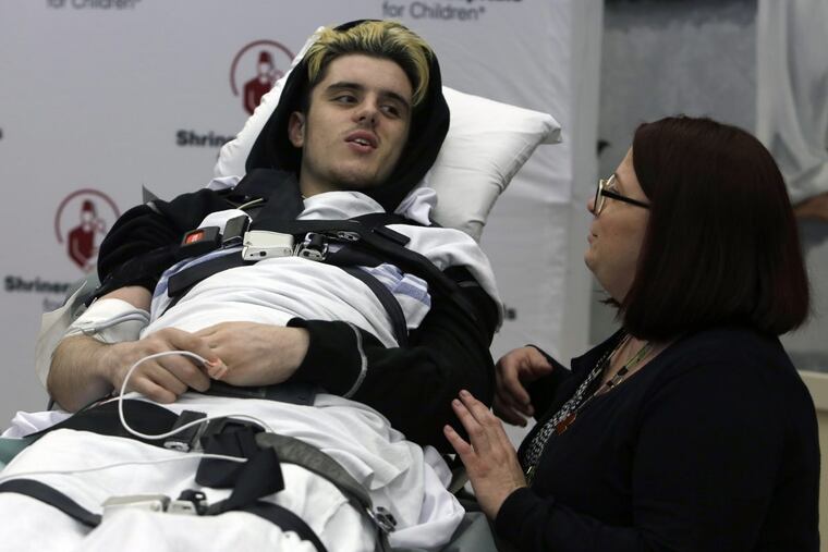 Care Manager Kim Curran, right, stands besides Ryan Straschnitzki after he was wheeled into Shriners Hospitals for Children.