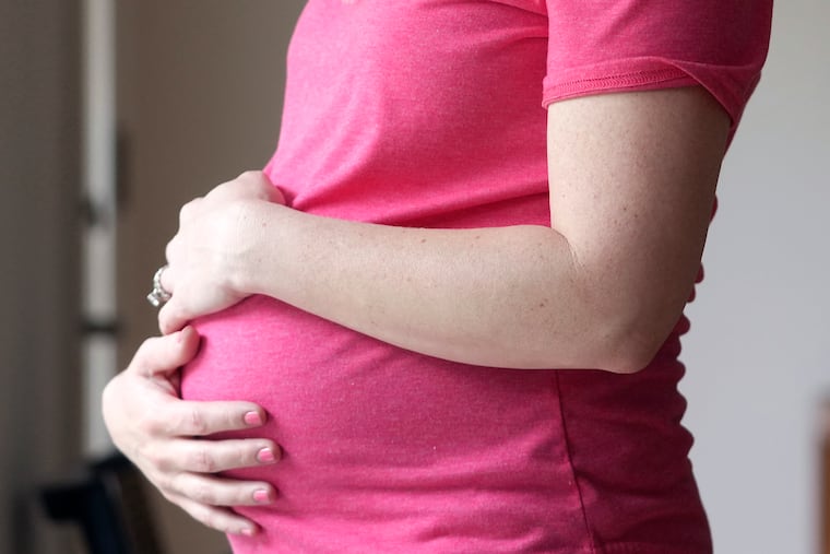 A pregnant woman stands for a portrait in Dallas in 2023.