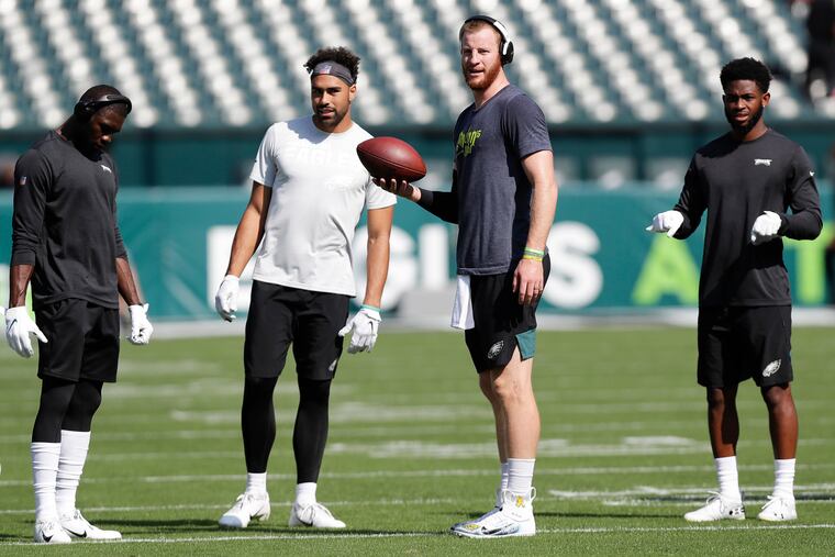 Eagles quarterback Carson Wentz holds the football with wide receivers (from left): Nelson Agholor, J.J. Arcega-Whiteside, and Greg Ward before the Lions game.