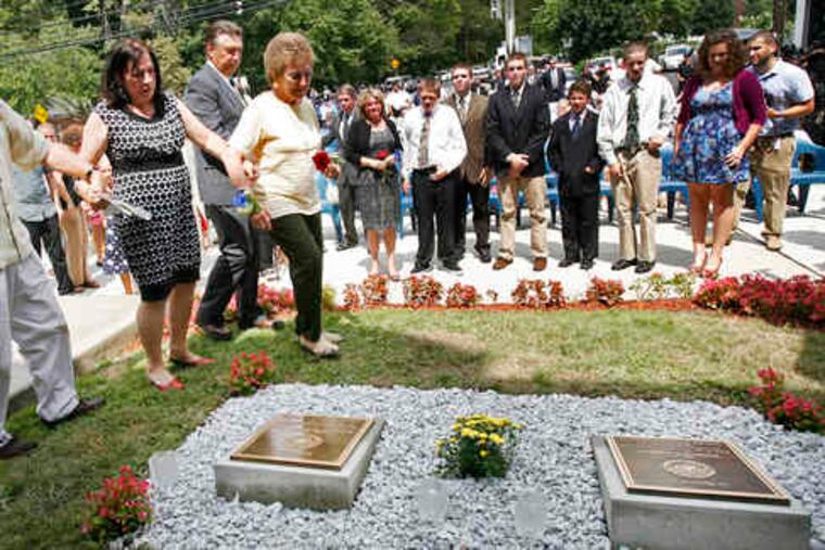 Members of the slain prison officials' families (left) approach the memorials outside the old Holmesburg Prison on Torresdale Avenue, where the two were attacked. Curran-Fromhold Correctional Facility on State Road was named for the pair.