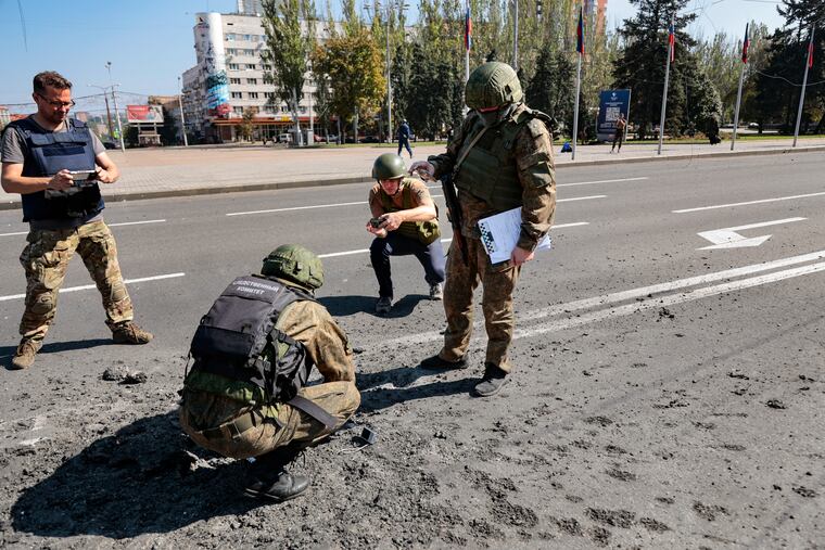 Investigators work at the site of a burning vehicle after shelling in Donetsk, area controlled by Russian-backed separatist forces, eastern Ukraine, on Saturday.