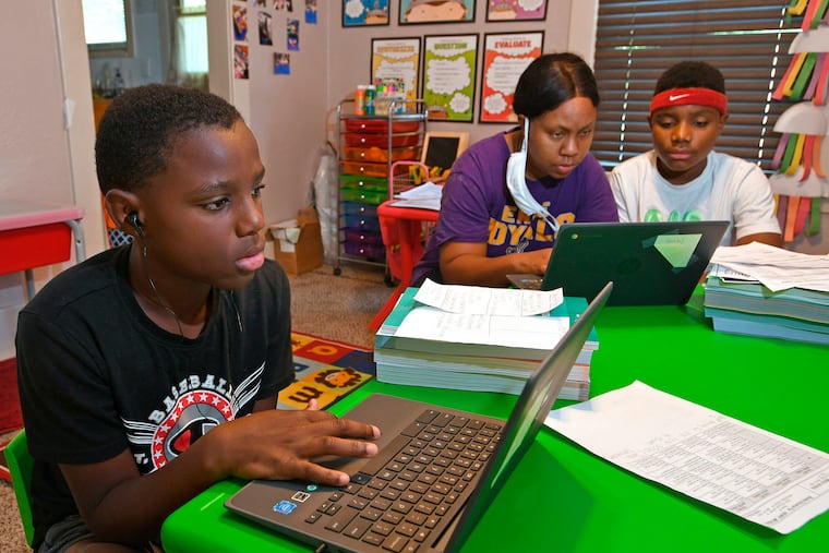 Michael Henry, 11, left, sits with his mother Mary Euell, center, and his brother Mario Henry, 12, as they work through math lessons remotely at their west Erie, Pa. on the first day of classes for the Erie School District in September. Gov. Tom Wolf asked lawmakers on Feb. 3 to raise income taxes on higher earners and give public schools a massive boost in aid, even as he faces a gaping deficit and uncertainty over how much more pandemic relief the federal government will send.