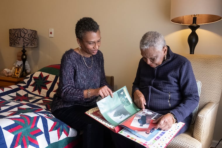 At Park Creek Place assisted living center in North Wales, Kim Boddy (left) and her mom, Marguerite Forbes, look through an album of family photos. Forbes often has trouble remembering her family members.