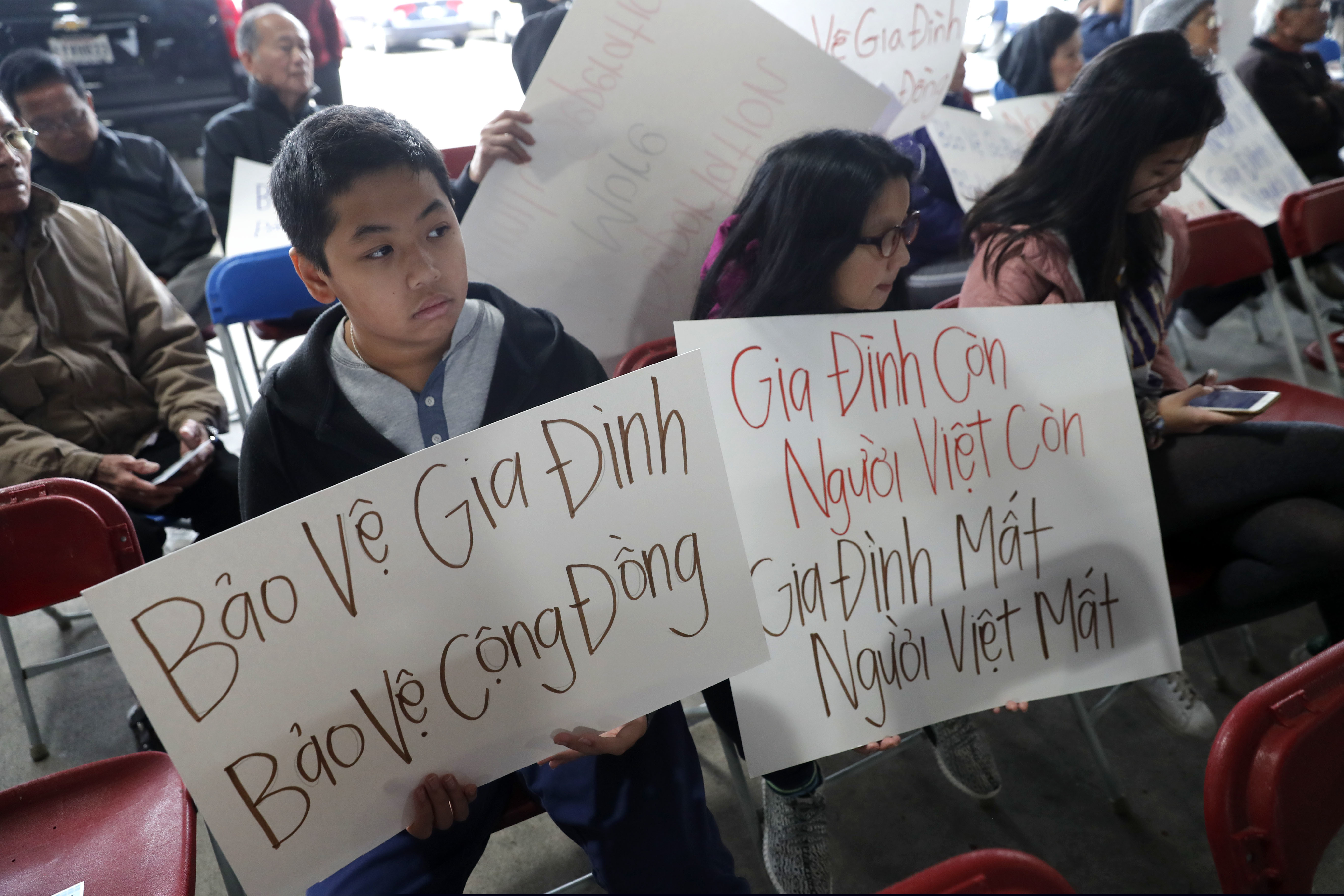 Bill Nguyen, 12, and Jade Nguyen, 9, hold signs at a rally protesting President Donald Trump's deportation policy to deport Vietnamese refugees, at the Mary Queen of Vietnam Church in New Orleans, Thursday, Dec. 20, 2018. (AP Photo/Gerald Herbert)