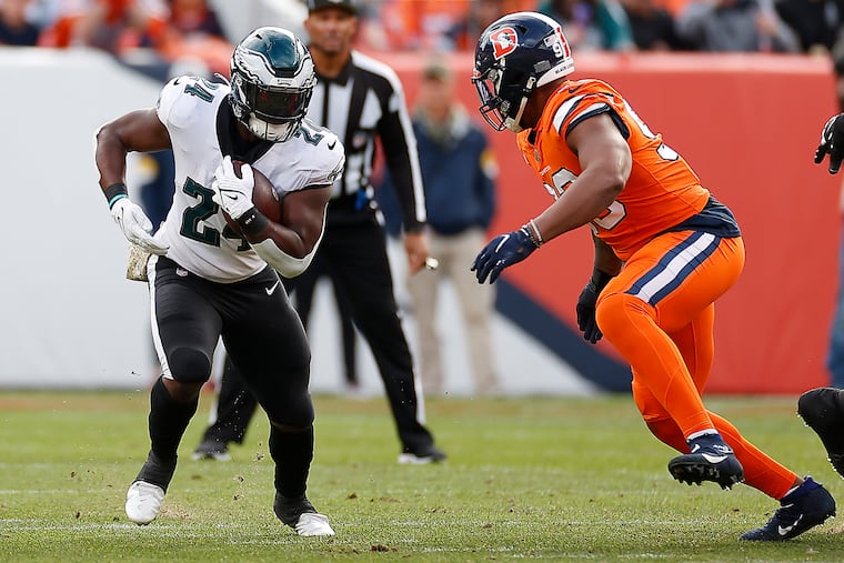 Eagles running back Jordan Howard (left) trying to avoid Denver Broncos defensive end Dre'Mont Jones on a run in the first quarter Sunday.
