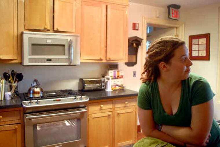 Food feeding creativity: Eleanor Kane, who graduated in '09 with a degree in English/creative writing, waits in the new kitchen for her chocolate chip cookies to bake. She's the daughter of Martha Wallace and Edward Kane, who donated money for the kitchen. Right, she puts cookies in the oven; also working are freshman English majors Hannah White (top), Sarah Schwab.