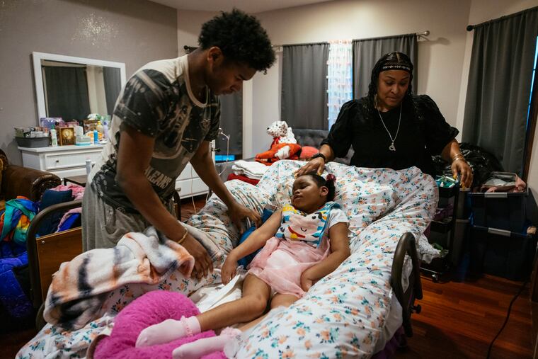 Tyrus Hike (left) helps his mother, Rhonda Jones, administer ibuprofen to Alayna Hike at their home in Crown Point, Ind. Alayna was injured during her birth and has cerebral palsy. She was recently hospitalized with respiratory syncytial virus, or RSV.