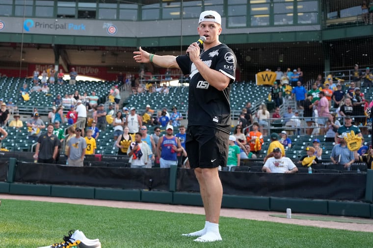 Eagles defensive back Cooper DeJean auctions off his custom cleats after the charity softball game at Principal Park in Des Moines, Iowa.
