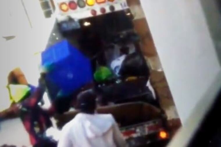 Philadelphia Streets Department workers toss residential recyclables in a blue bucket in with trash in South Philadelphia in November, 2020.