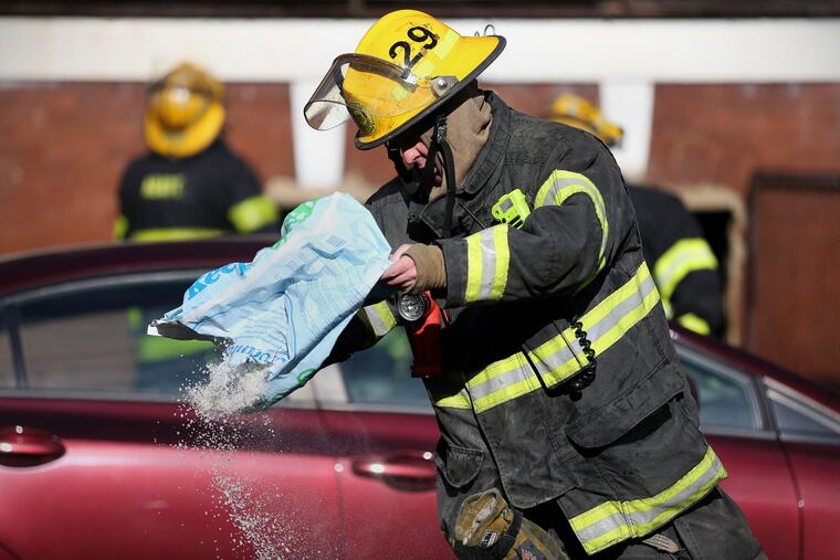 A firefighter spreads ice melt to prevent water from freezing on the street after battling a multi-alarm fire that damaged apartments in the 4900 block of Walnut Street in West Philadelphia on Friday, Dec. 29, 2017.