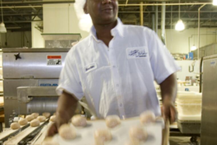 At LeBus Bakery, employee Mouctar K. Diabaté loads a tray onto a baking rack.