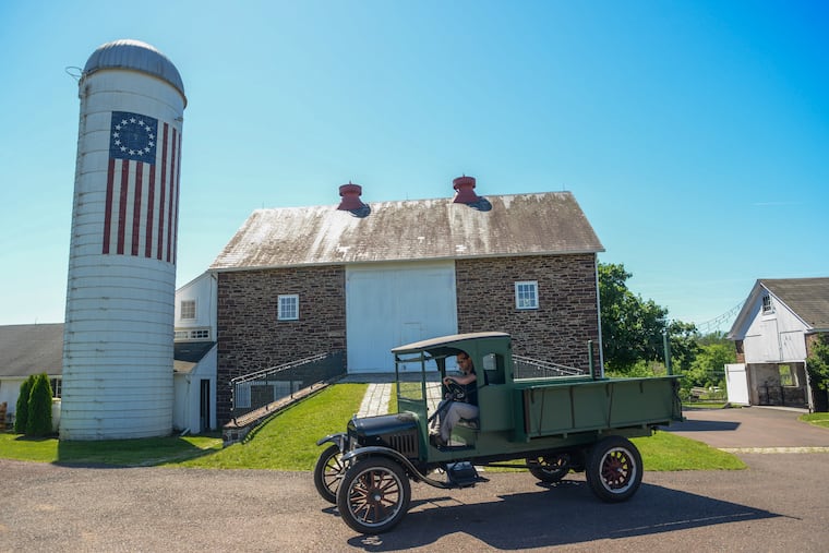 Kevin Roberts drives an antique truck in front of the barn at Durham Hill Farm, where his family runs a wedding event business.