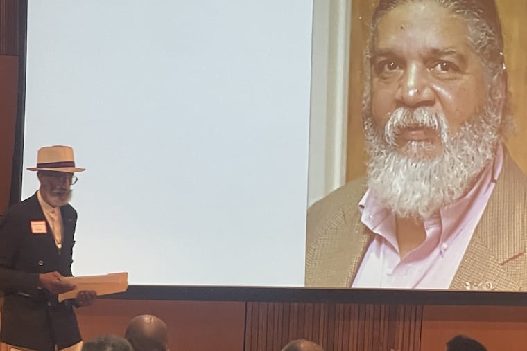Philadelphia artist Richard Watson leaves the stage at the Pennsylvania Academy of Fine Arts after giving a tribute to Lewis Tanner Moore, pictured on the screen.