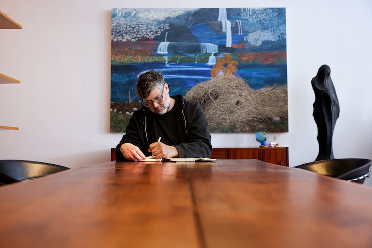 Joe Beddia, of Pizzeria Beddia, sketches at his home in Old City. The painting behind him, "Emerald Street" by Becky Suss, is one of his favorites from his collection.