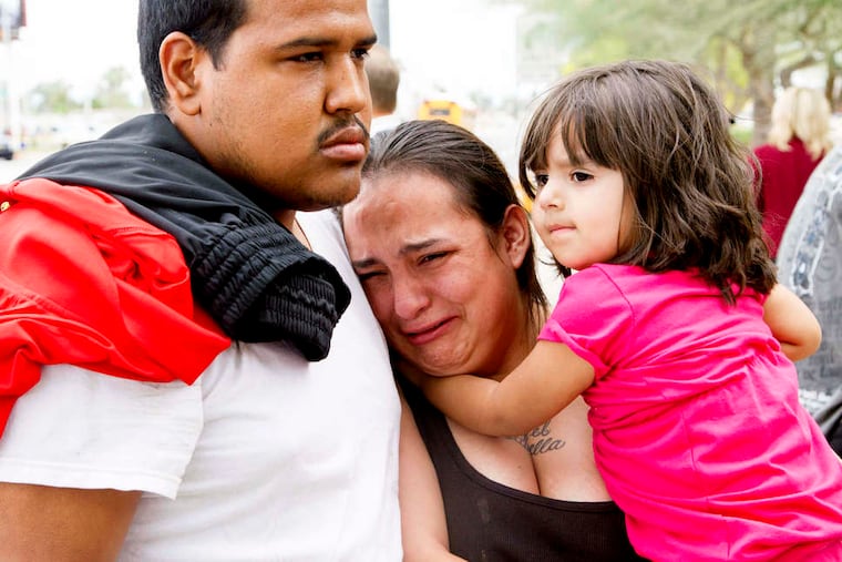 Tanya Ehrig cries for victims of a shooting rampage as she holds daughter Trinity. The alleged gunman, who had served three stints in prison, was taken into custody after being shot with a stun gun.