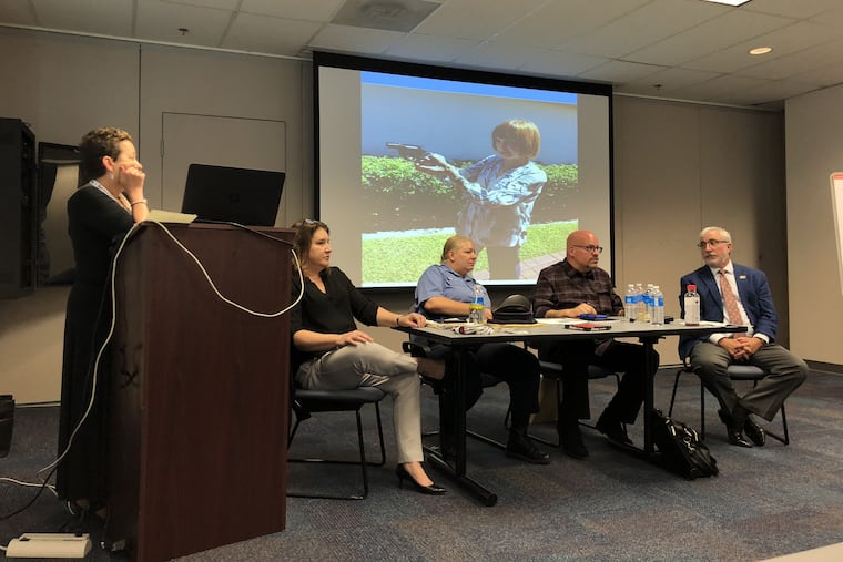 Ilene Warner-Maron, a nurse, listens at the podium while a panel discusses the dangers of guns and older adults with dementia or depression. From left, they are Jennifer Spoeri, director of older adult protective services at Philadelphia Corporation for aging; officers Tracy Lewis and Rick Brehant from the Philadelphia Police Department, and Fritz Walker, secretary of the board of directors of CeaseFirePA, A photo of Warner-Maron's mother and her gun served as a backdrop.